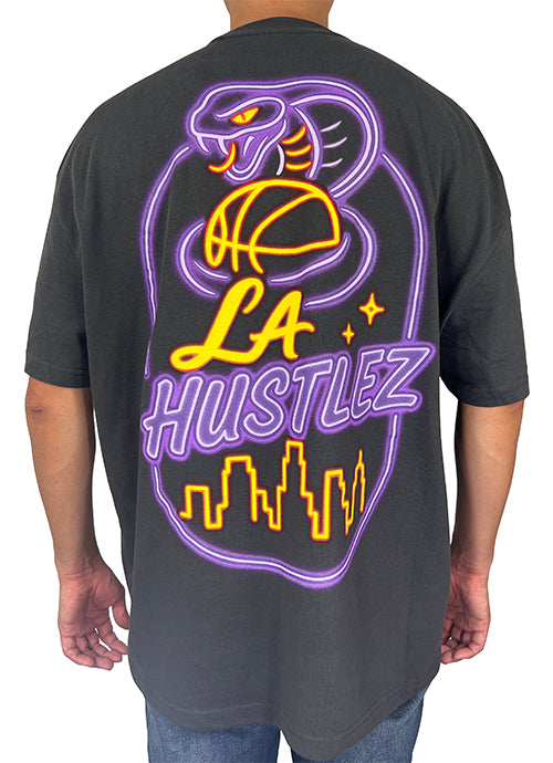 Person wearing a black t-shirt with 'LA Hustlez' graphic design on the back.